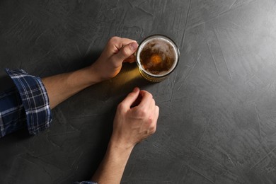 Photo of Man with glass mug of beer at grey table, top view. Space for text