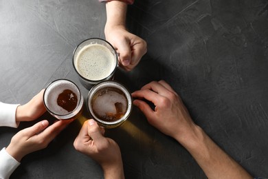 Photo of Friends with glasses of beer at grey table, top view