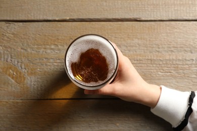 Photo of Woman with glass of beer at wooden table, top view
