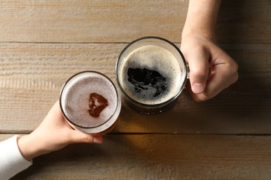 Photo of Friends with glasses of beer at wooden table, top view