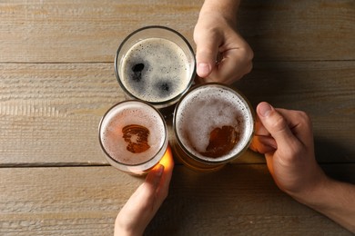 Photo of Friends with glasses of beer at wooden table, top view