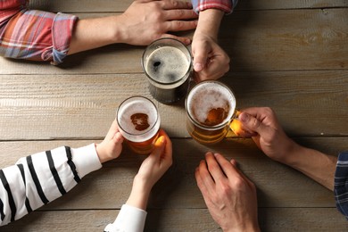 Photo of Friends with glasses of beer at wooden table, top view