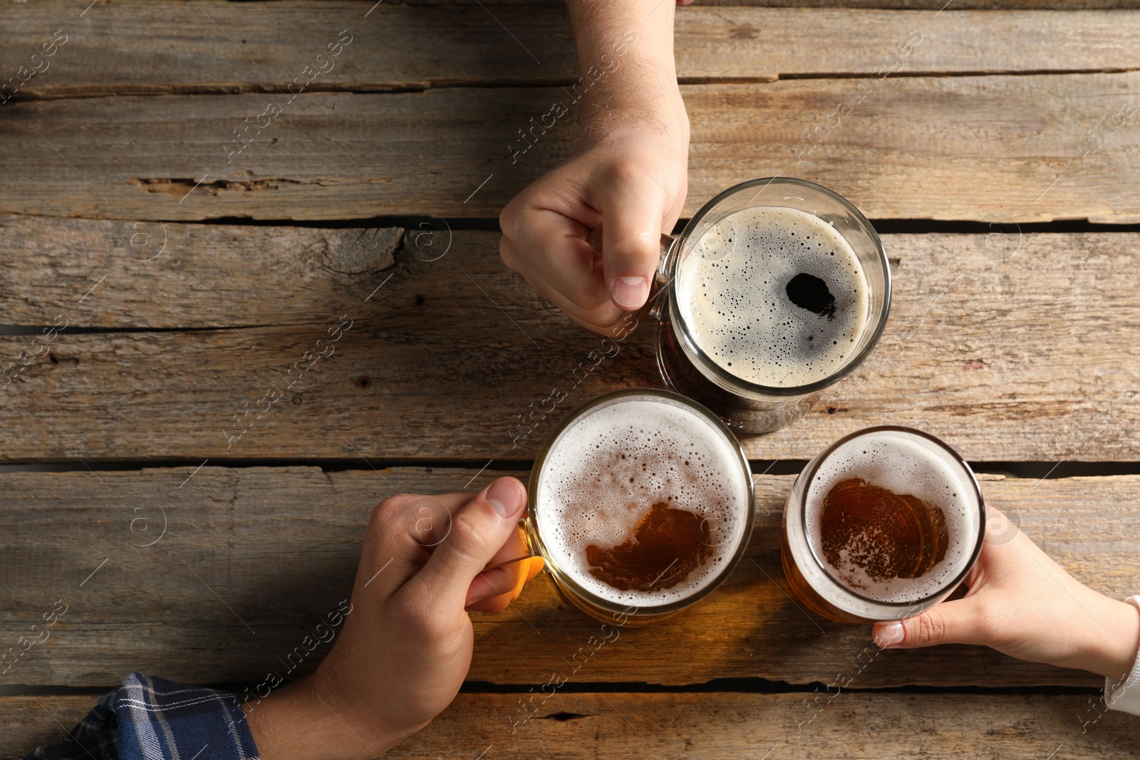 Photo of Friends with glasses of beer at wooden table, top view. Space for text