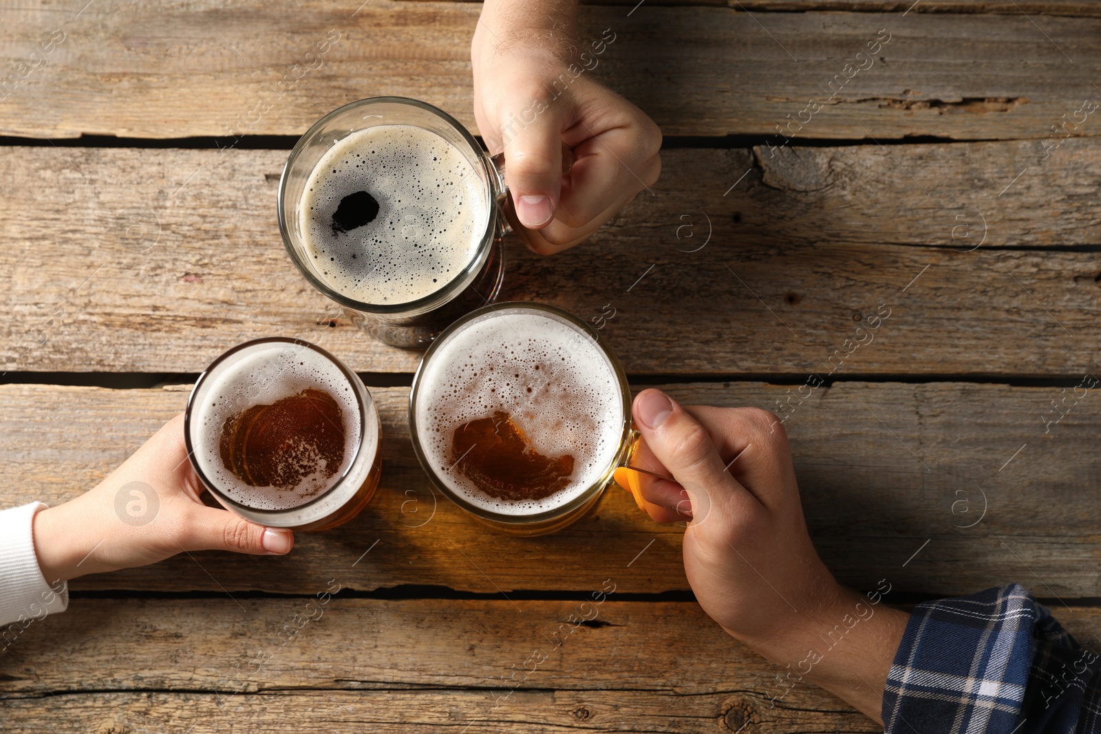 Photo of Friends with glasses of beer at wooden table, top view