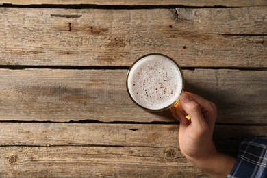 Photo of Man with glass mug of beer at wooden table, top view. Space for text