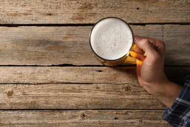 Photo of Man with glass mug of beer at wooden table, top view. Space for text