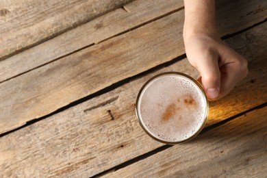 Photo of Man with glass mug of beer at wooden table, top view. Space for text