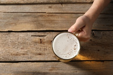 Photo of Man with glass mug of beer at wooden table, top view. Space for text