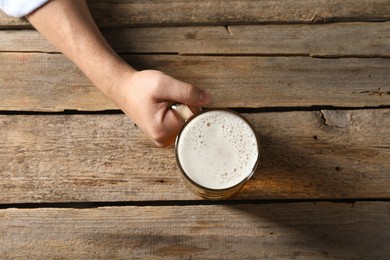 Photo of Man with glass mug of beer at wooden table, top view