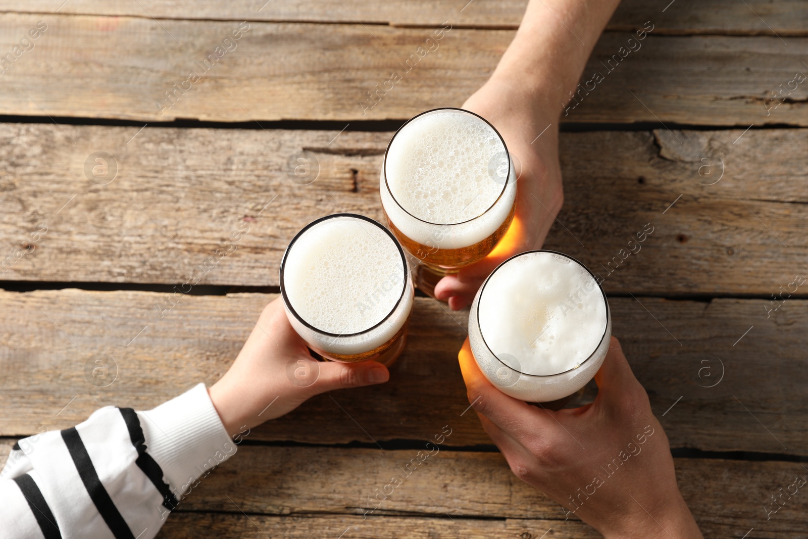 Photo of Friends with glasses of beer at wooden table, top view