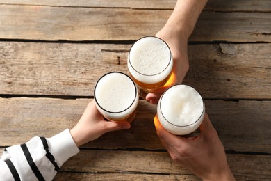 Photo of Friends with glasses of beer at wooden table, top view