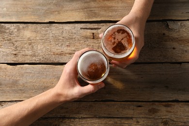 Photo of Friends with glasses of beer at wooden table, top view