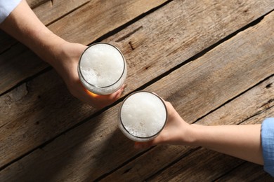 Photo of Friends with glasses of beer at wooden table, top view
