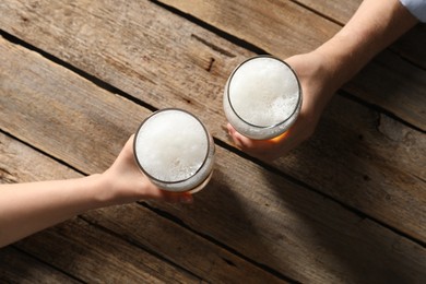 Photo of Friends with glasses of beer at wooden table, top view