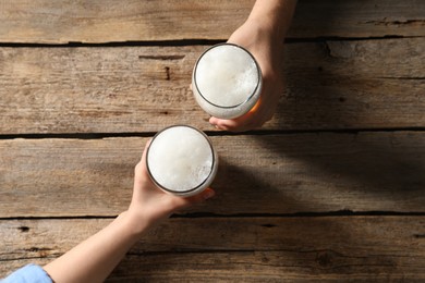 Photo of Friends with glasses of beer at wooden table, top view