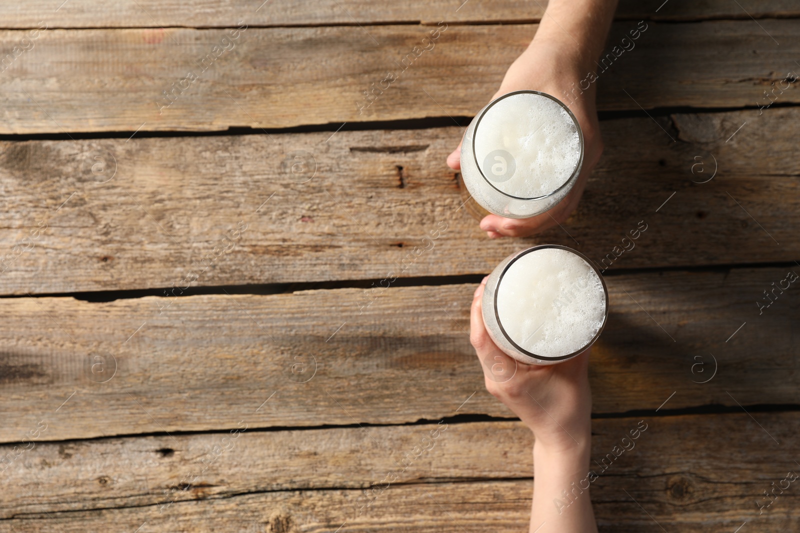 Photo of Friends with glasses of beer at wooden table, top view. Space for text