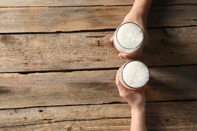 Photo of Friends with glasses of beer at wooden table, top view. Space for text