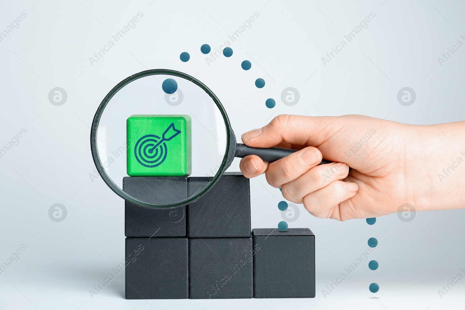 Targeting, business strategy, planning. Woman holding magnifying glass in front of green cube with bullseye icon, closeup Image of Targeting, business strategy, planning. Woman holding magnifying glass in front of green cube with bullseye icon, closeup
