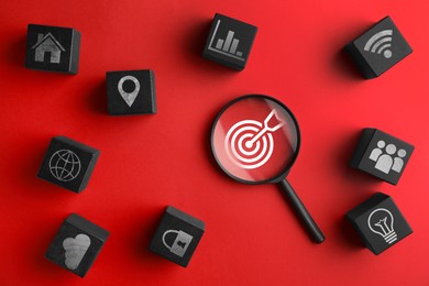 Image of Targeting, business strategy, planning. Magnifying glass with bullseye and black cubes with different icons on red background, top view