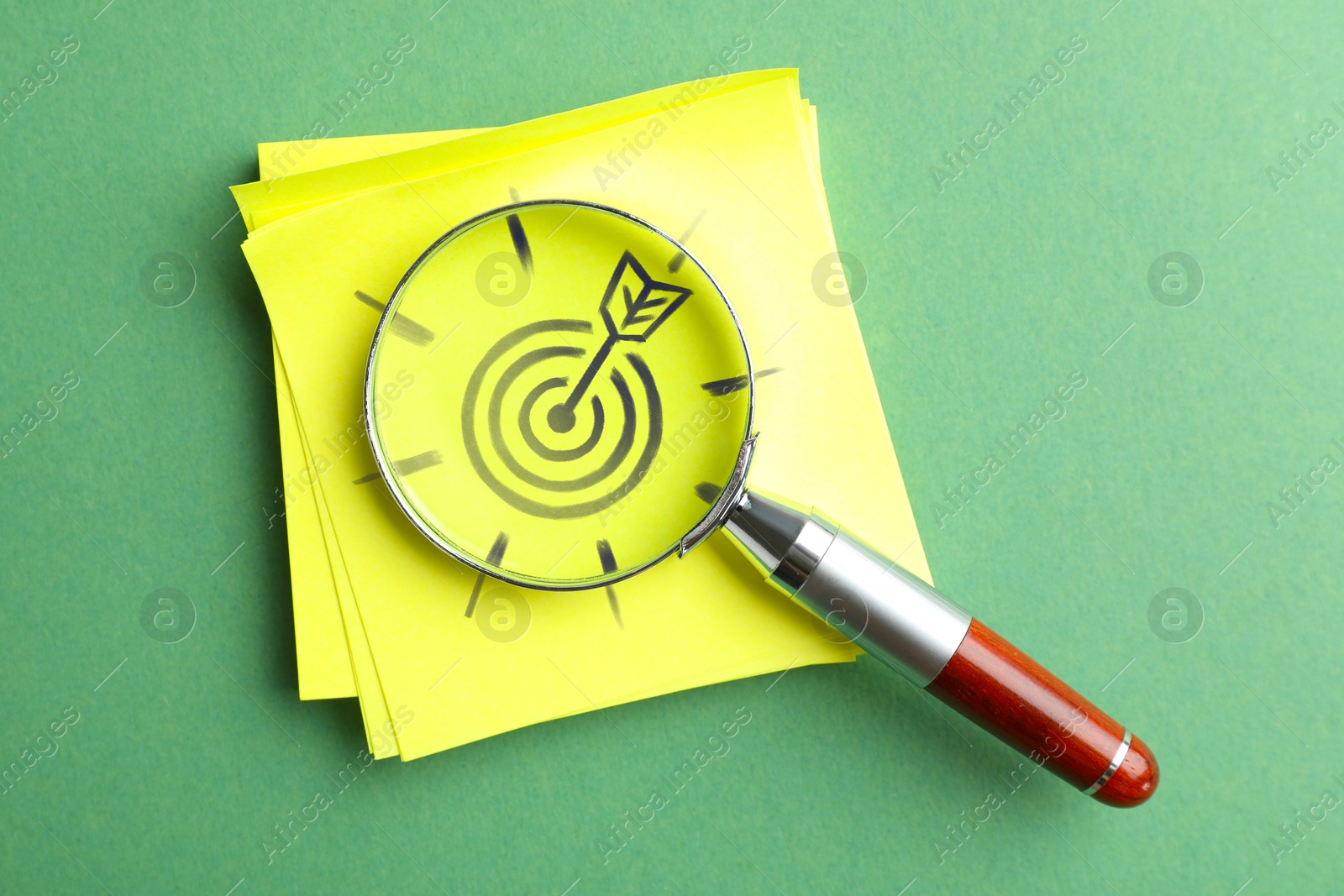 Targeting. Magnifying glass on paper note with bullseye on light green background, top view Image of Targeting. Magnifying glass on paper note with bullseye on light green background, top view
