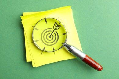 Image of Targeting. Magnifying glass on paper note with bullseye on light green background, top view
