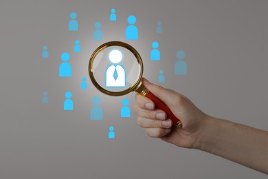 Image of Targeting. Woman holding magnifying glass over human icons against light grey background, closeup