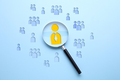 Image of Targeting. Magnifying glass and human icons against light blue background, top view