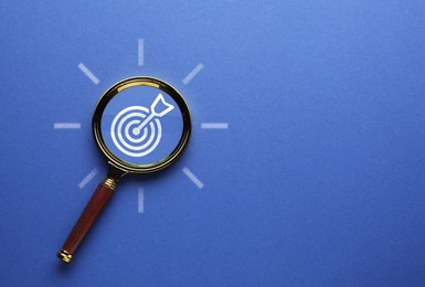Image of Targeting. Magnifying glass with bullseye on blue background, top view