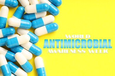 Image of World antibiotic awareness week. Many pills on yellow background, flat lay