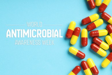 Image of World antibiotic awareness week. Many pills on light blue background, flat lay