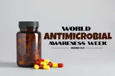 Image of World antibiotic awareness week. Bottle and scattered pills on grey background