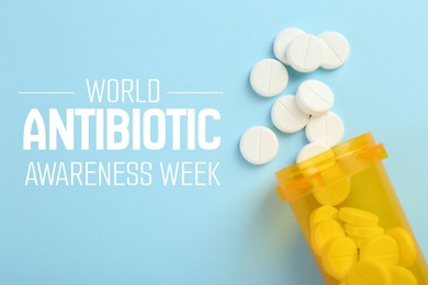 Image of World antibiotic awareness week. Bottle and scattered pills on light blue background, flat lay