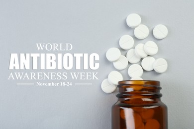 Image of World antibiotic awareness week. Bottle and scattered pills on grey background, flat lay