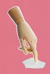 Image of Wooden hand pointing at piece of paper on pink background