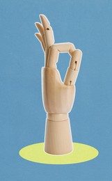 Image of Wooden mannequin hand showing okay gesture on blue background