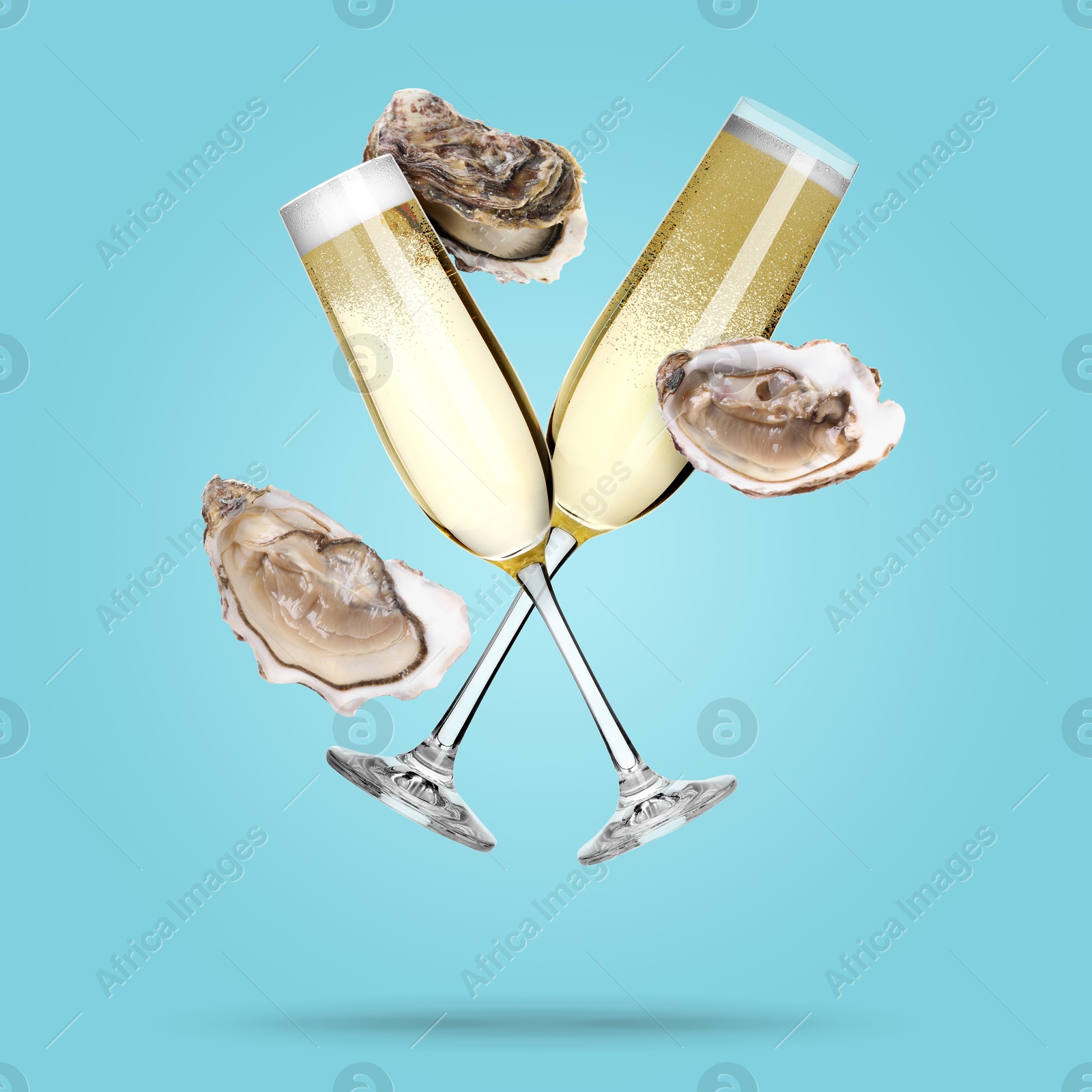 Image of Sparkling wine in glasses and fresh oysters falling on light blue background