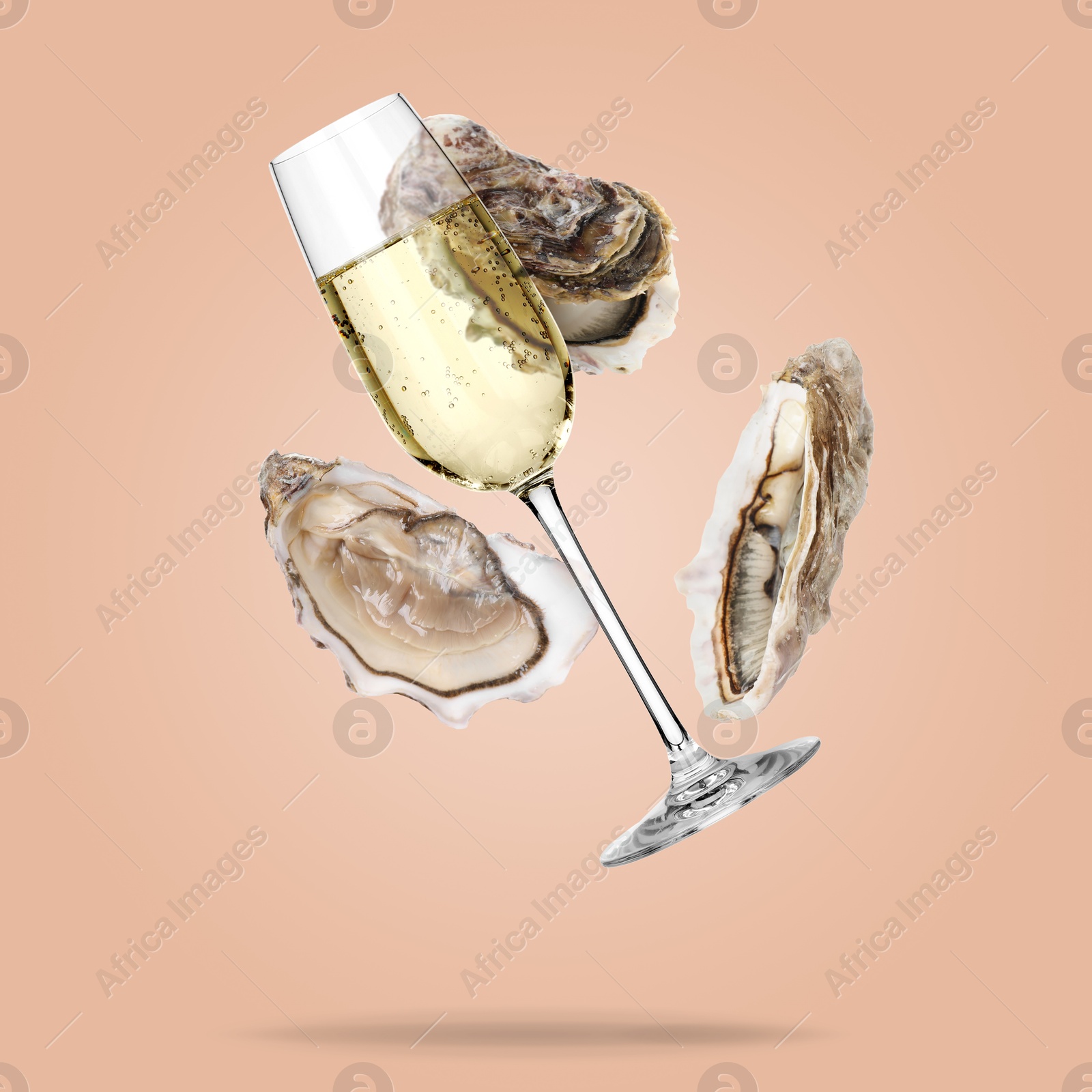 Image of Sparkling wine in glass and fresh oysters falling on pink beige background