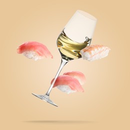 Image of White wine in glass and nigiri sushi falling on beige background