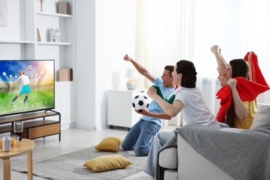 Image of Football fans watching soccer match on TV set at home