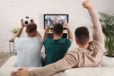 Image of Football fans watching soccer match on TV set at home, back view