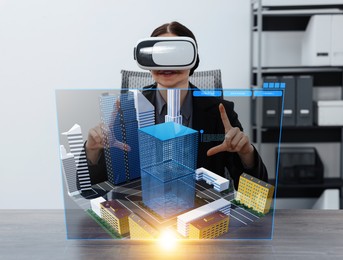 Image of Building information modelling. Woman using virtual reality headset in office. Holographic screen with cityscape