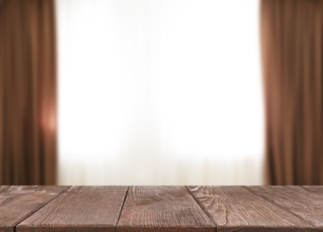 Image of Empty wooden table against window with curtains in room