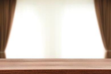 Image of Empty wooden table against window with curtains in room
