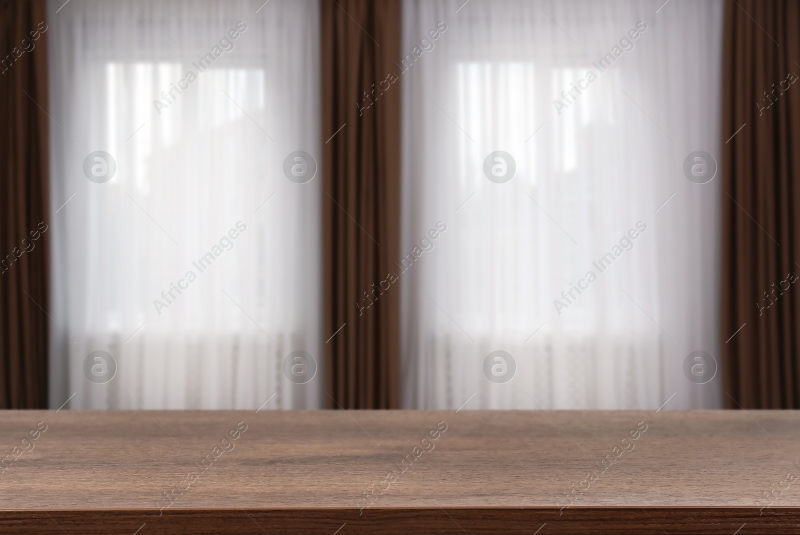 Image of Empty wooden table against windows with curtains in room