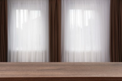 Image of Empty wooden table against windows with curtains in room