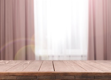 Image of Empty wooden table against window with curtains in room
