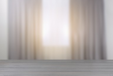 Image of Empty wooden table against window with curtains in room