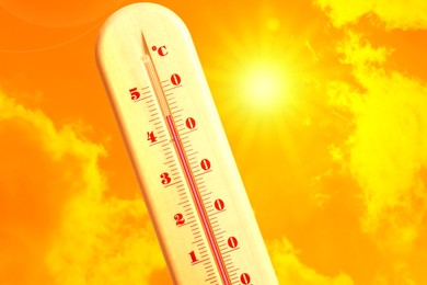 Image of Extremely high temperature on thermometer against orange sky on sunny day. Severely hot summer weather