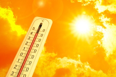 Image of Extremely high temperature on thermometer against orange sky on sunny day. Severely hot summer weather