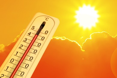 Image of Extremely high temperature on thermometer against orange sky on sunny day. Severely hot summer weather